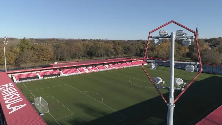 Cột đèn pha rực sáng trên sân Peninsula Stadium, nơi Salford City FC thi đấu