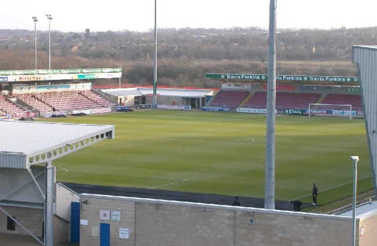 Hình ảnh sân vận động Sixfields trước một trận đấu, mô tả bầu không khí yên bình